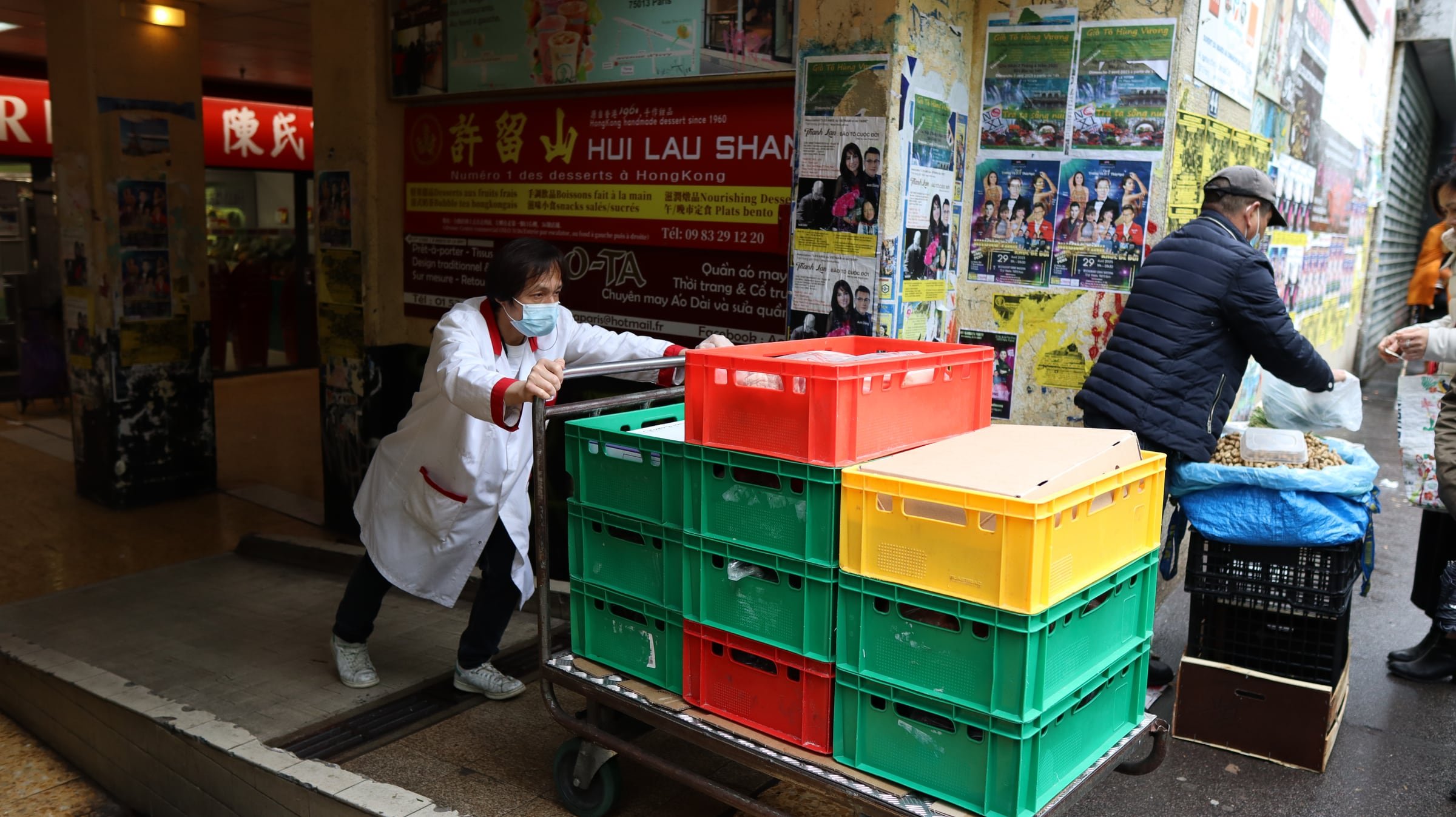 Stacked green, red and yellow crates on a delivery cart outside an Asian supermarket in Paris’s 13th arrondissement.
